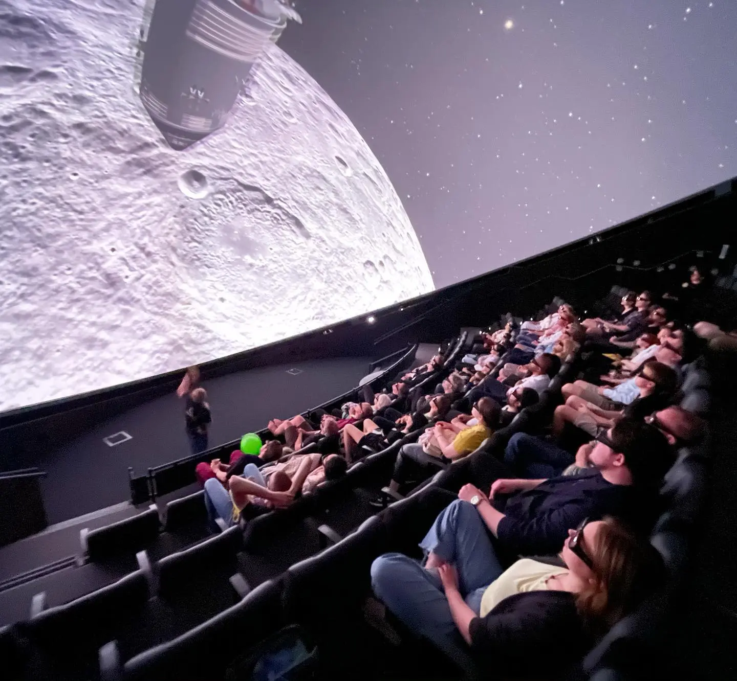 Audience in a dome theater watching an OpenSpace visualization of the Moon